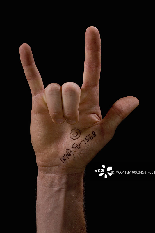 手掌写有电话号码的男人做出摇滚手势，特写镜头图片素材