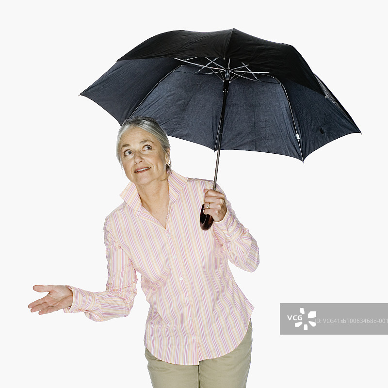 手持雨伞向上看的年长女性图片素材