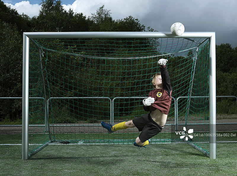 在球门柱旁跳起来接球的男孩（8-9岁）图片素材