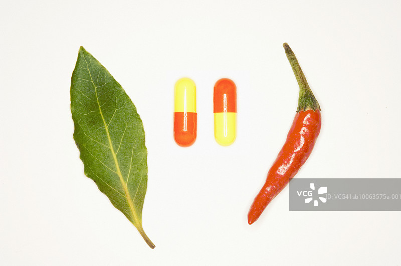 两粒药用胶囊与月桂叶和辣椒，影棚拍摄图片素材