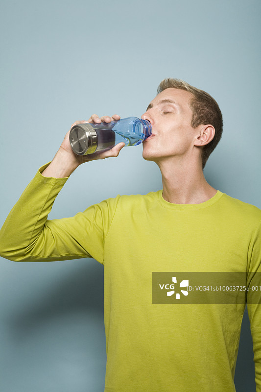 闭着眼睛的年轻男人喝瓶装水图片素材