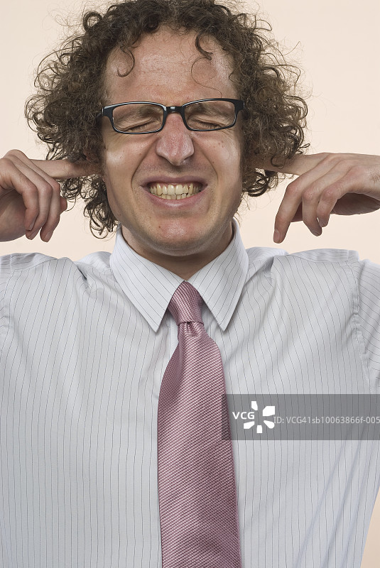 特写：闭着眼睛，用手指堵住耳朵的商人图片素材