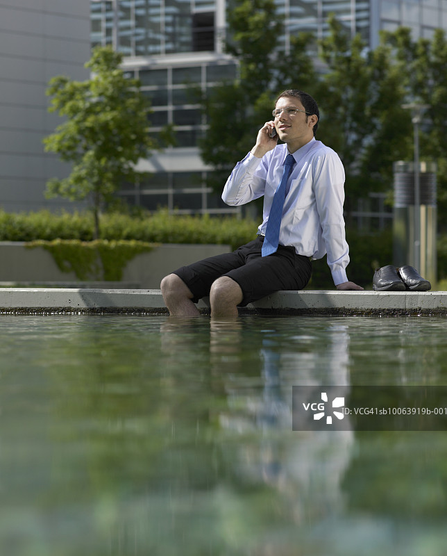在公园里打电话，脚在水里的商人图片素材