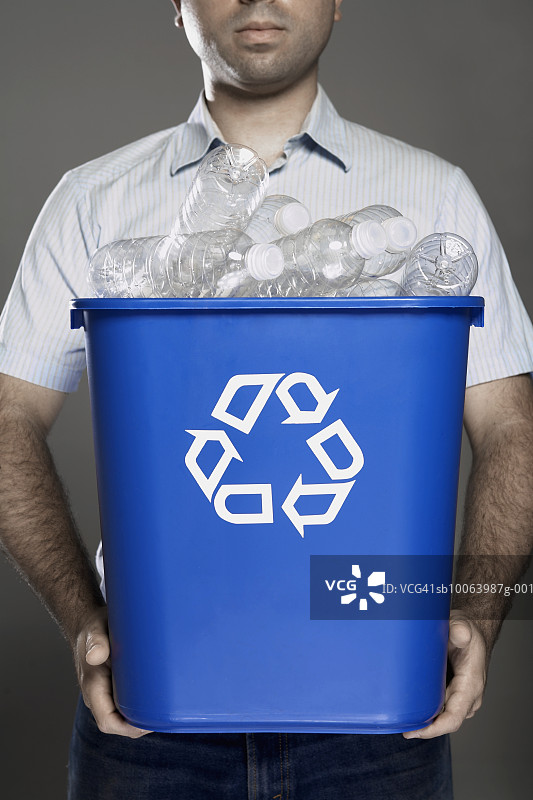 男人拿着装满空塑料瓶的回收箱（中部视角）图片素材