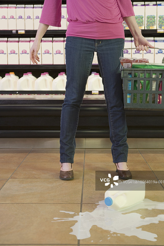 中年妇女站在超市里，牛奶洒了一地图片素材