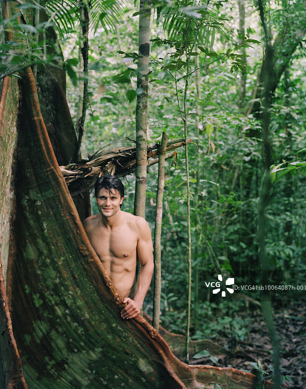 站在热带雨林树干旁的男人肖像图片素材