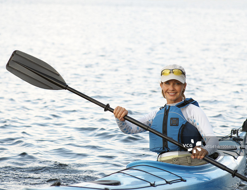 穿着救生衣在皮划艇上的中年妇女，面带微笑的肖像图片素材