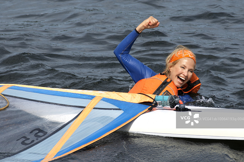 在湖里玩帆板，笑着的中年妇女图片素材