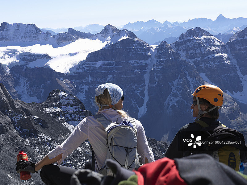情侣坐在悬崖边，背景是雪山图片素材