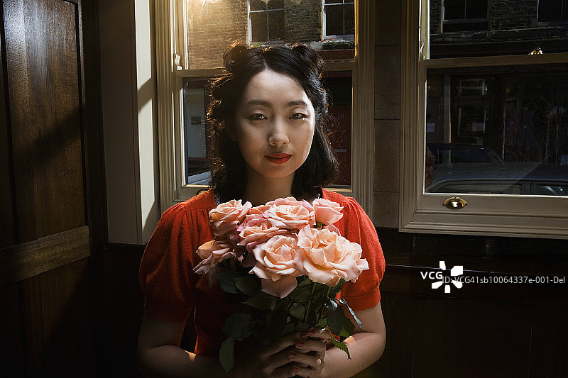 手捧玫瑰微笑的女人图片素材