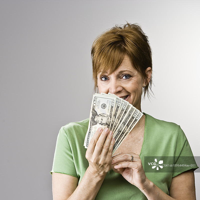 手持一叠钞票的中年妇女，影棚人像图片素材