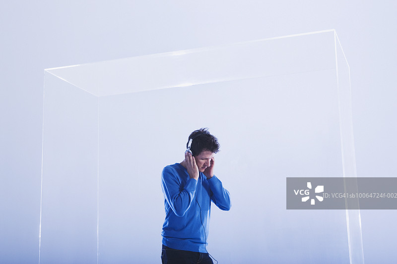 年轻男人在玻璃柜里听音乐图片素材