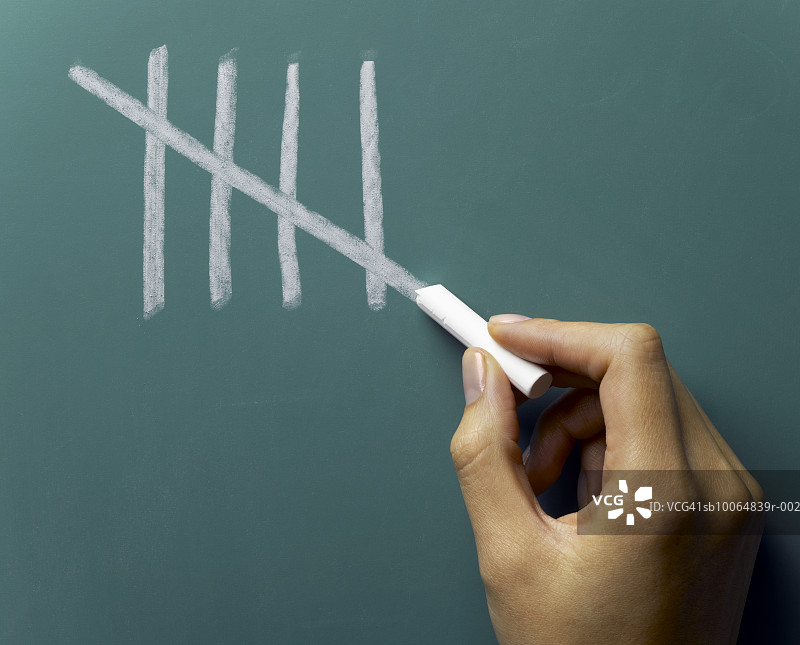女人手在黑板上做第五个刻痕，特写图片素材