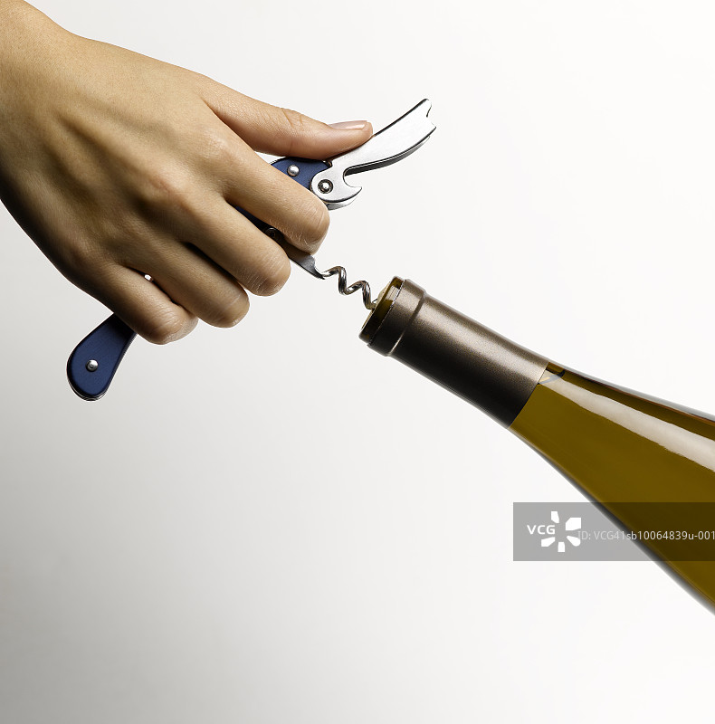 女人拔出葡萄酒瓶的软木塞图片素材
