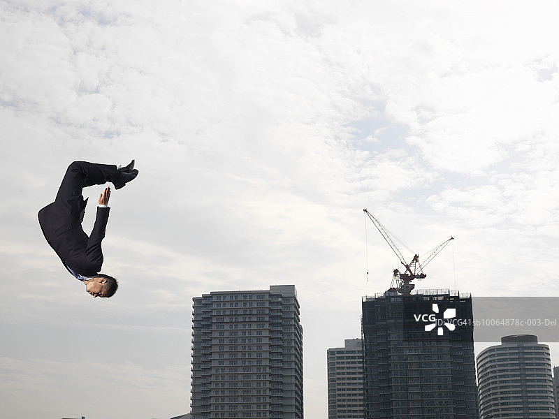 商人翻筋斗，背景是摩天大楼，低角度图片素材