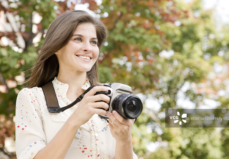 拿着相机微笑的年轻女人图片素材