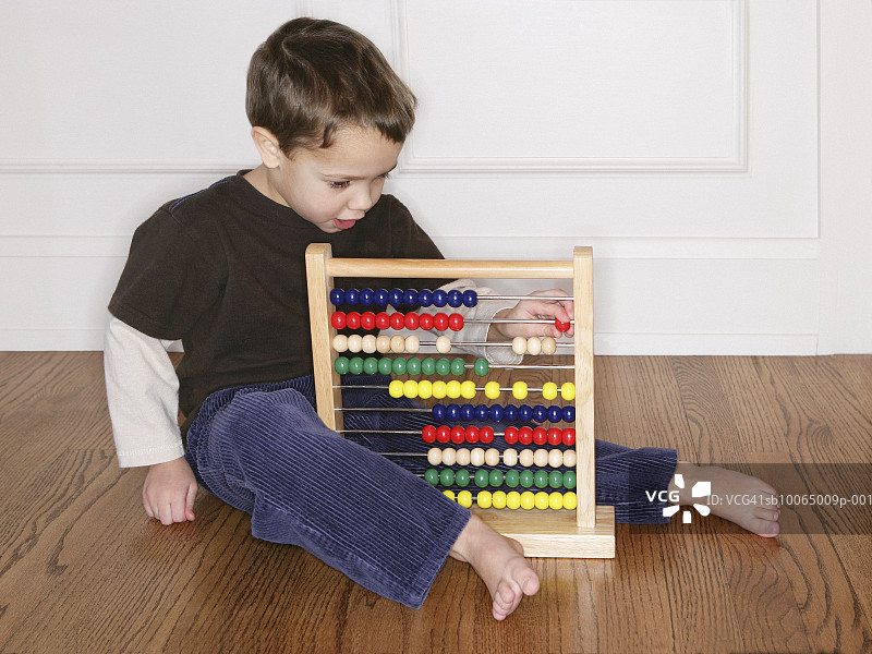 在地上玩算盘的4-5岁男孩图片素材