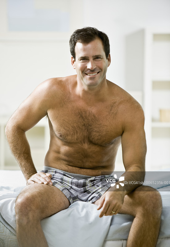 身穿内衣坐在床上的男人肖像图片素材
