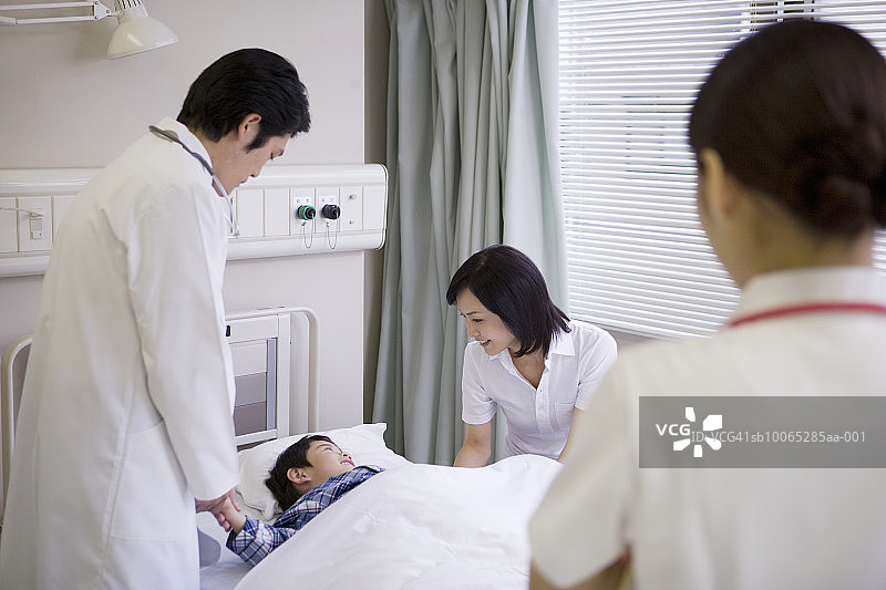 护士看着医生和母亲与卧床男孩（5-6岁）交谈图片素材