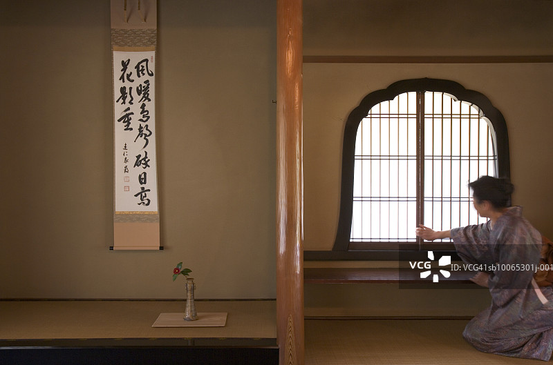 穿和服在茶室调整窗户的女人图片素材