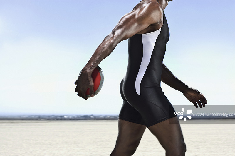 运动员在干涸的湖面上拿着铁饼行走图片素材