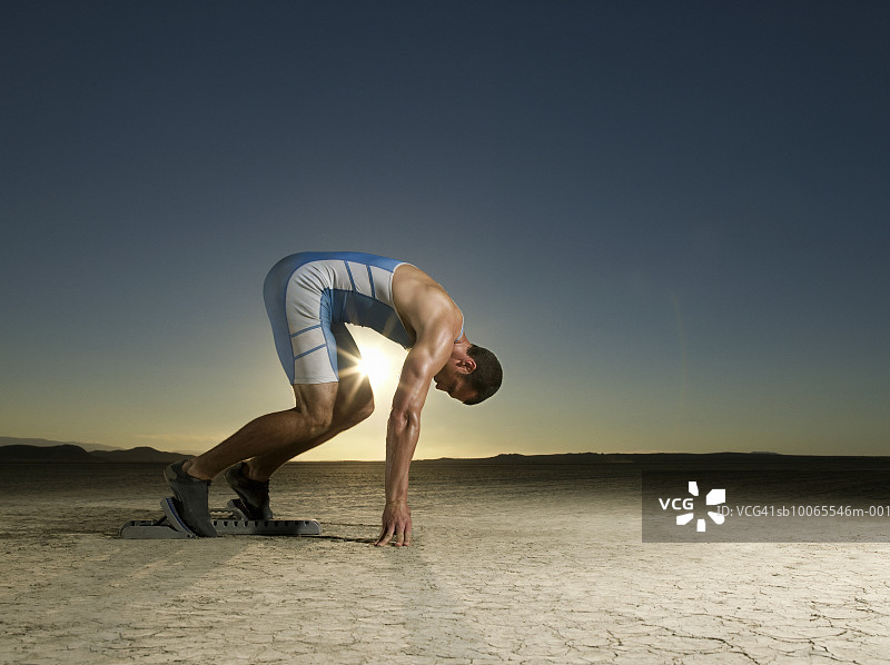 黄昏时站在起跑器上的运动员（侧面）图片素材