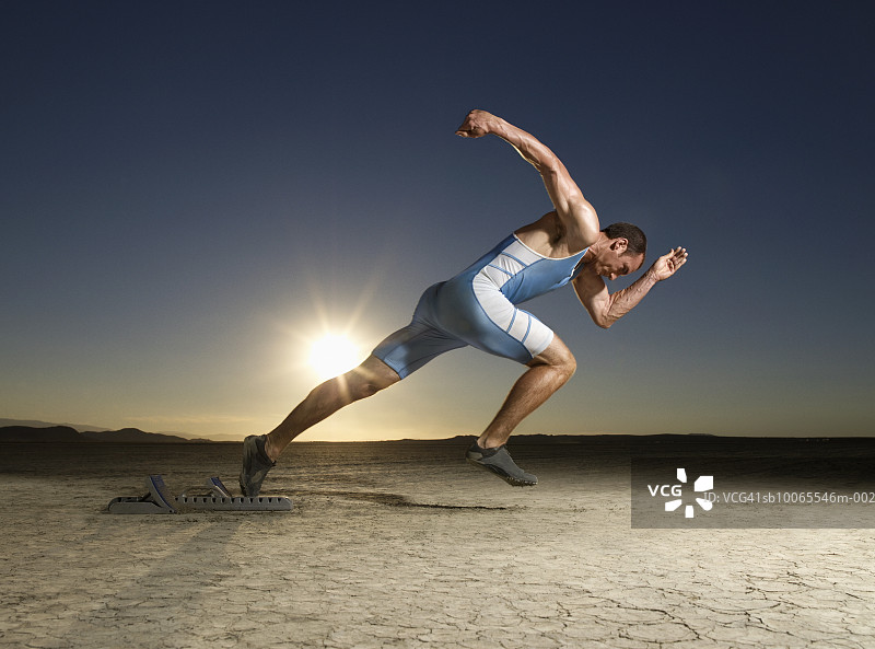 运动员在黄昏时从起跑器起跑，侧视图图片素材