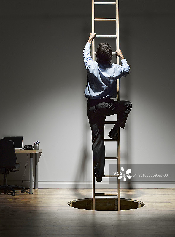 男子从木地板的洞里爬上梯子，后视图图片素材