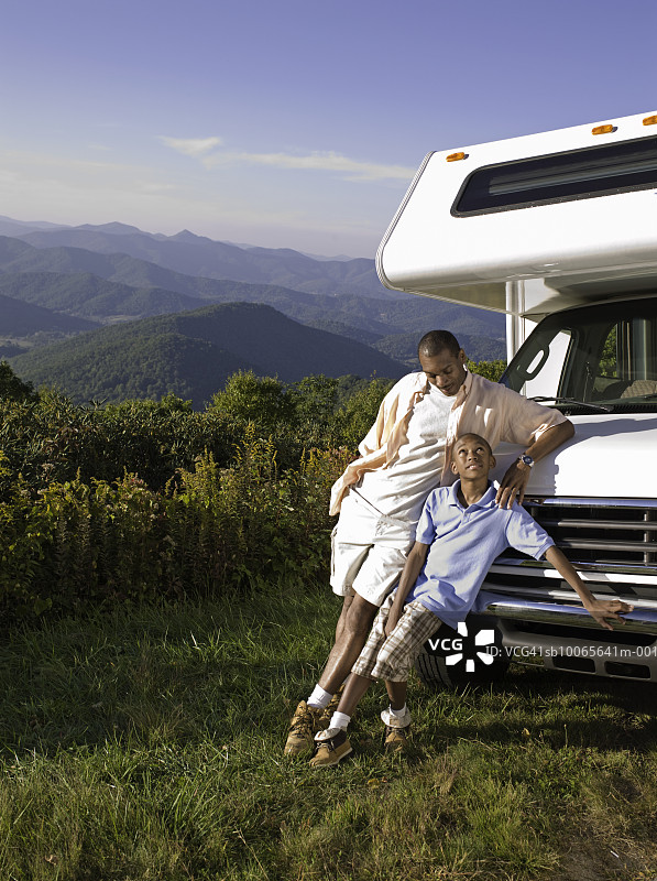 父亲和儿子（12-13岁）靠在房车上图片素材