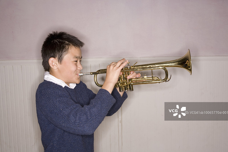 吹小号的青少年男孩（14-15岁），侧视图图片素材