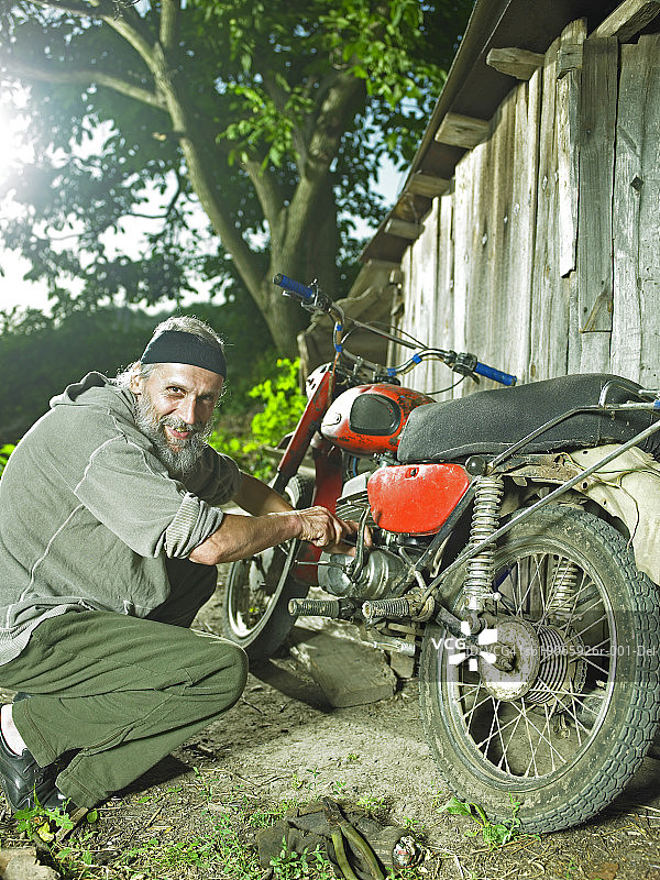 年长的男人修理自行车，面带微笑，肖像图片素材