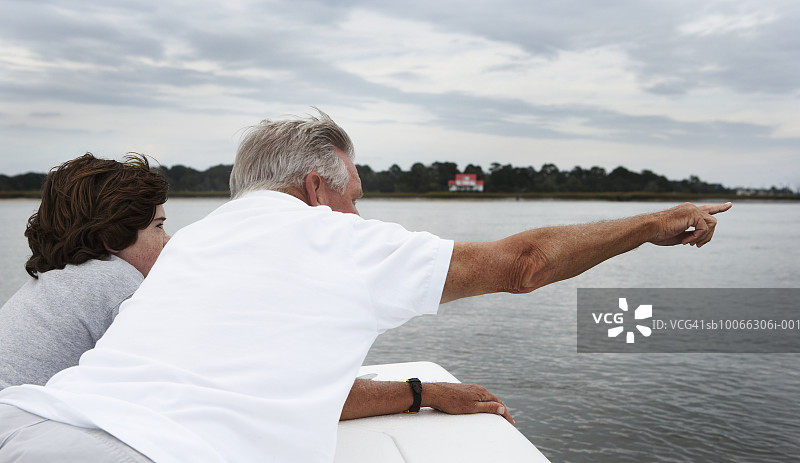 和孙子（10-11岁）在船上观看风景的老年男人图片素材
