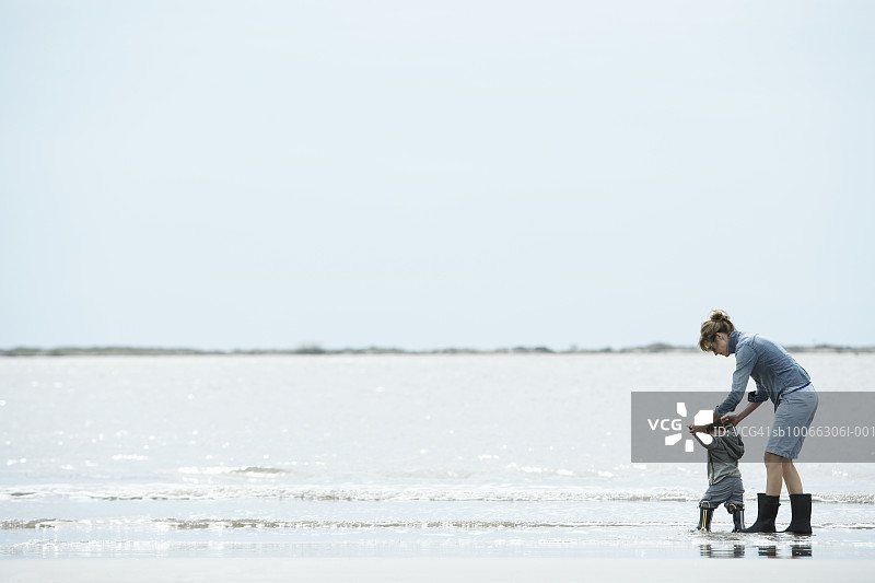 母亲和儿子（15-18个月）在岸边行走图片素材