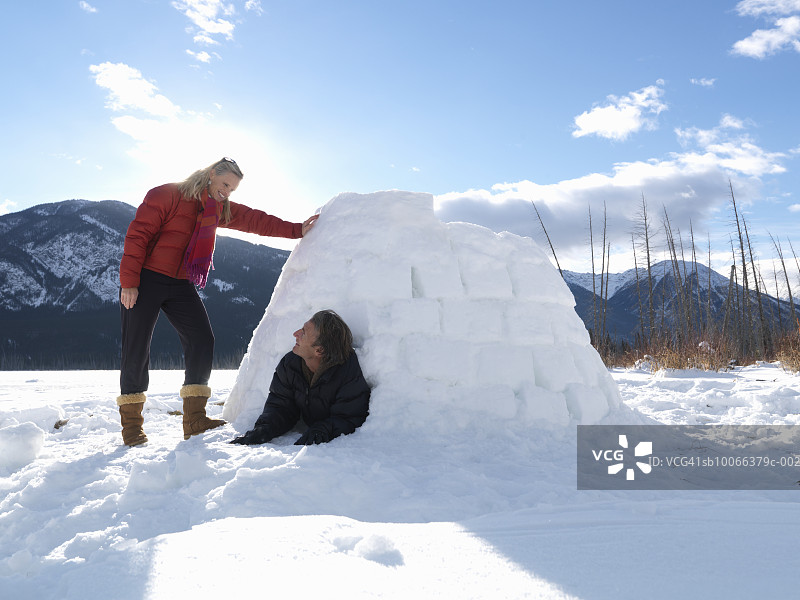 中年夫妇在冰雪覆盖的湖面上玩冰屋，面带笑容图片素材