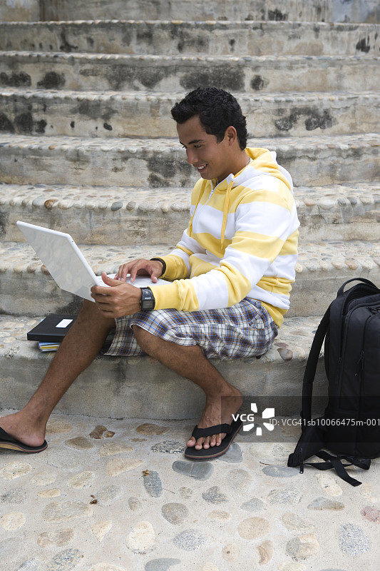 年轻男子在楼梯上做学校作业图片素材