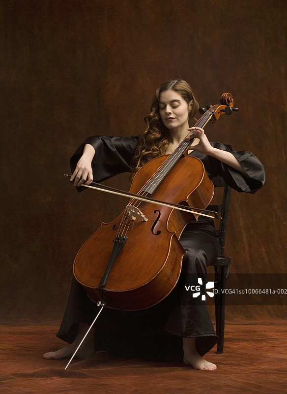 年轻女人坐着演奏大提琴图片素材