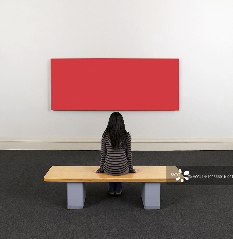年轻女子在美术馆观赏画作，后视图图片素材