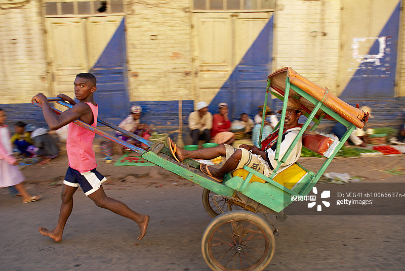 马达加斯加：安博西特拉，贝齐莱奥，年轻人拉着载有乘客的人力车沿街行驶图片素材
