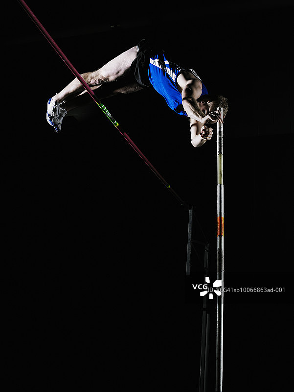 男性撑杆跳运动员越过横杆图片素材