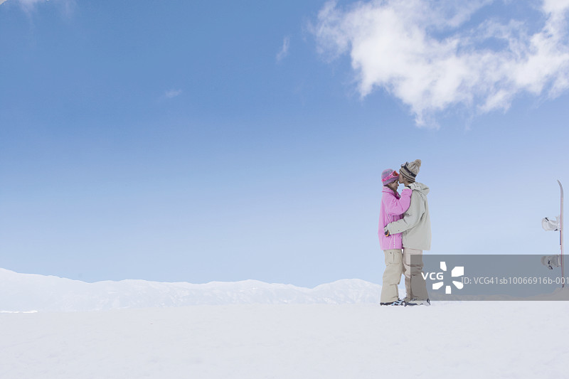 情侣在雪地里，滑雪板旁亲吻图片素材