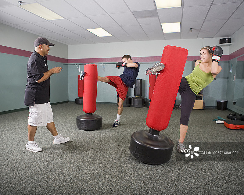 在健身房与运动教练练习跆拳道的年轻男女图片素材