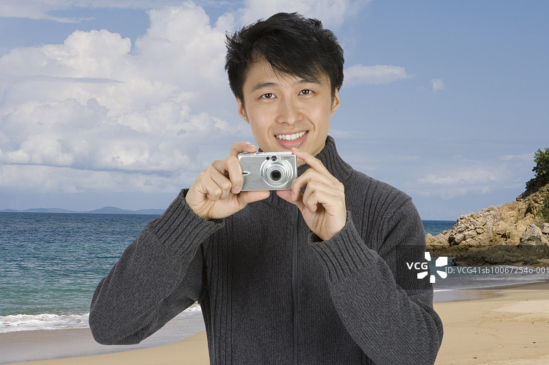 男人使用数码相机，背景是热带海滩图片素材