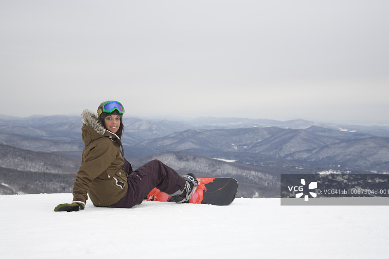 以山为背景的年轻单板滑雪女子肖像图片素材