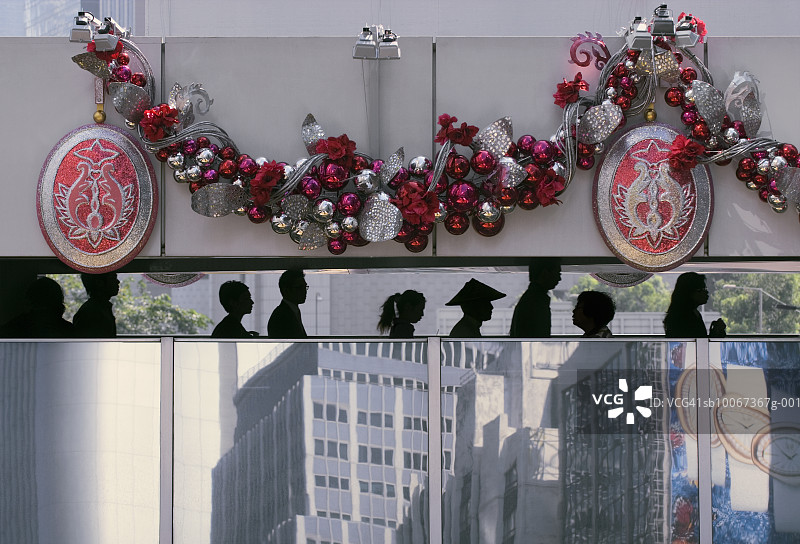 高架走道上的人群剪影，墙上的圣诞装饰图片素材