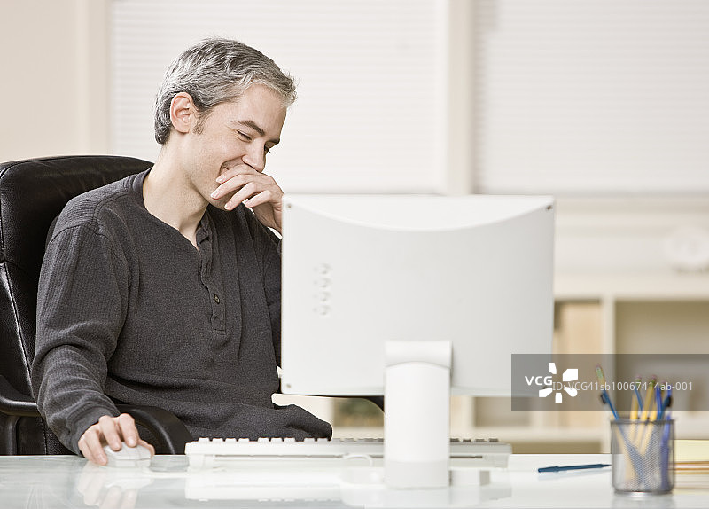 男人坐在办公桌旁使用电脑图片素材