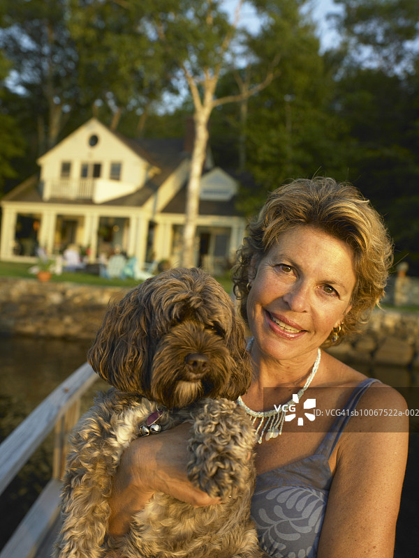 抱着狗微笑的中年妇女肖像图片素材