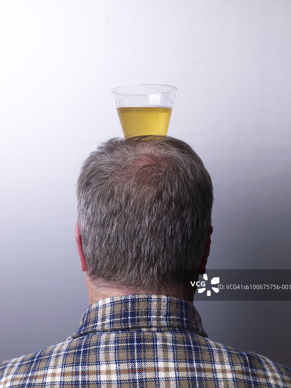 头顶啤酒的男子背影摄影棚照图片素材