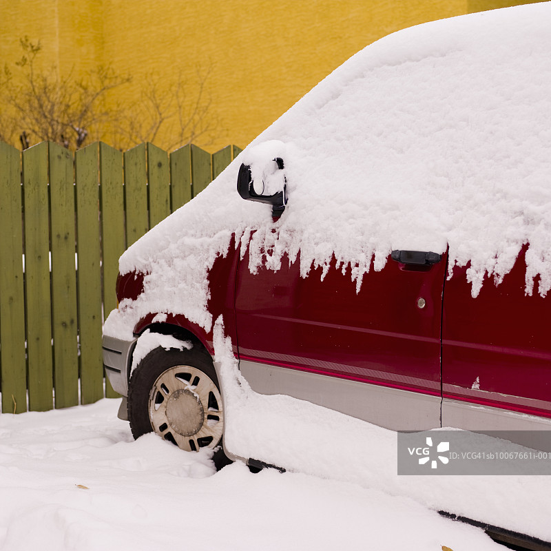 被雪覆盖的停靠在栅栏边的厢型车图片素材
