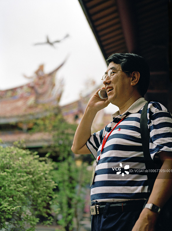 中国台湾台北龙山寺内使用手机的男人图片素材