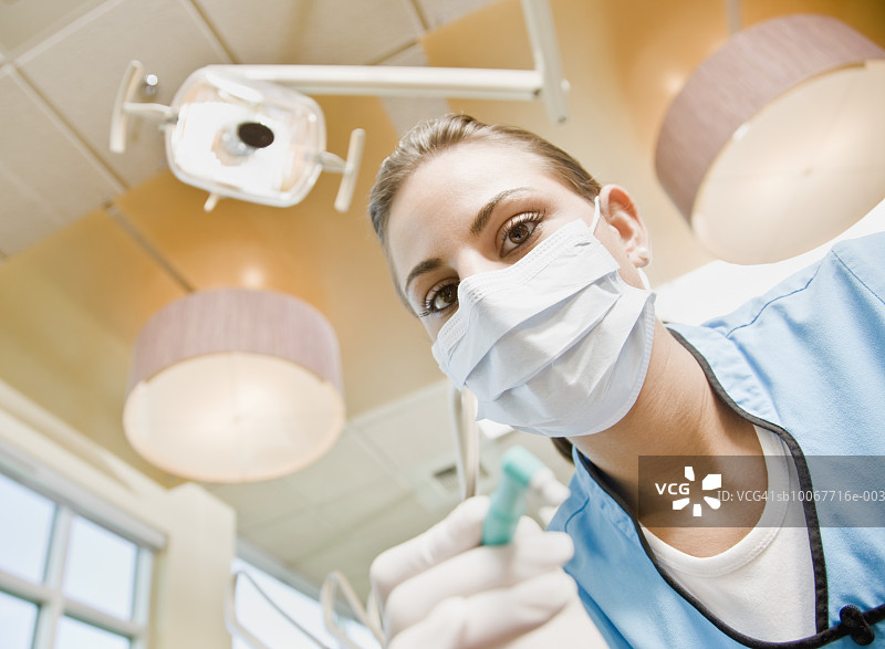 手持牙科工具的女牙科助理，低角度特写肖像图片素材